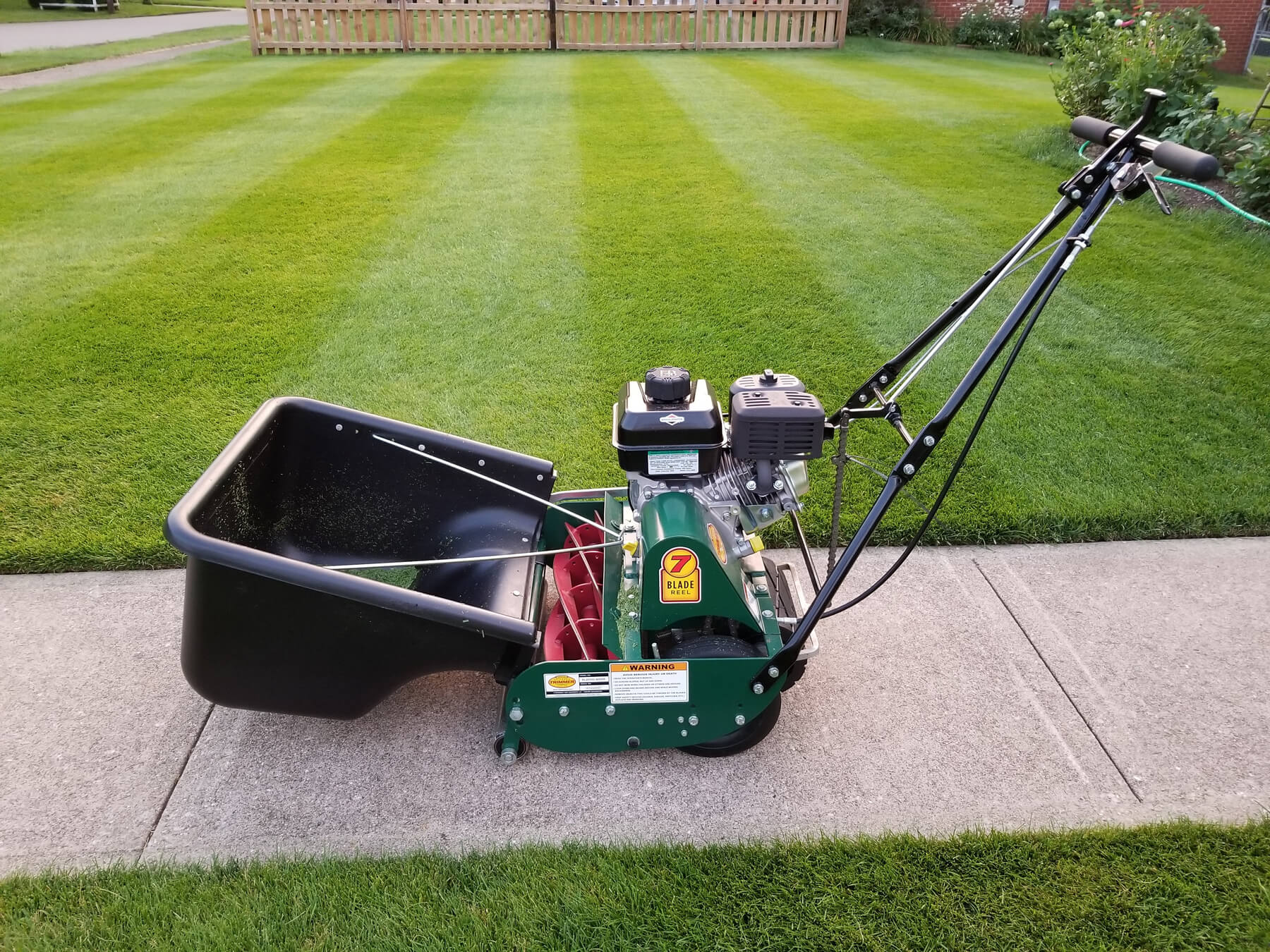 blade reel mower with bucket attachment in a front yard