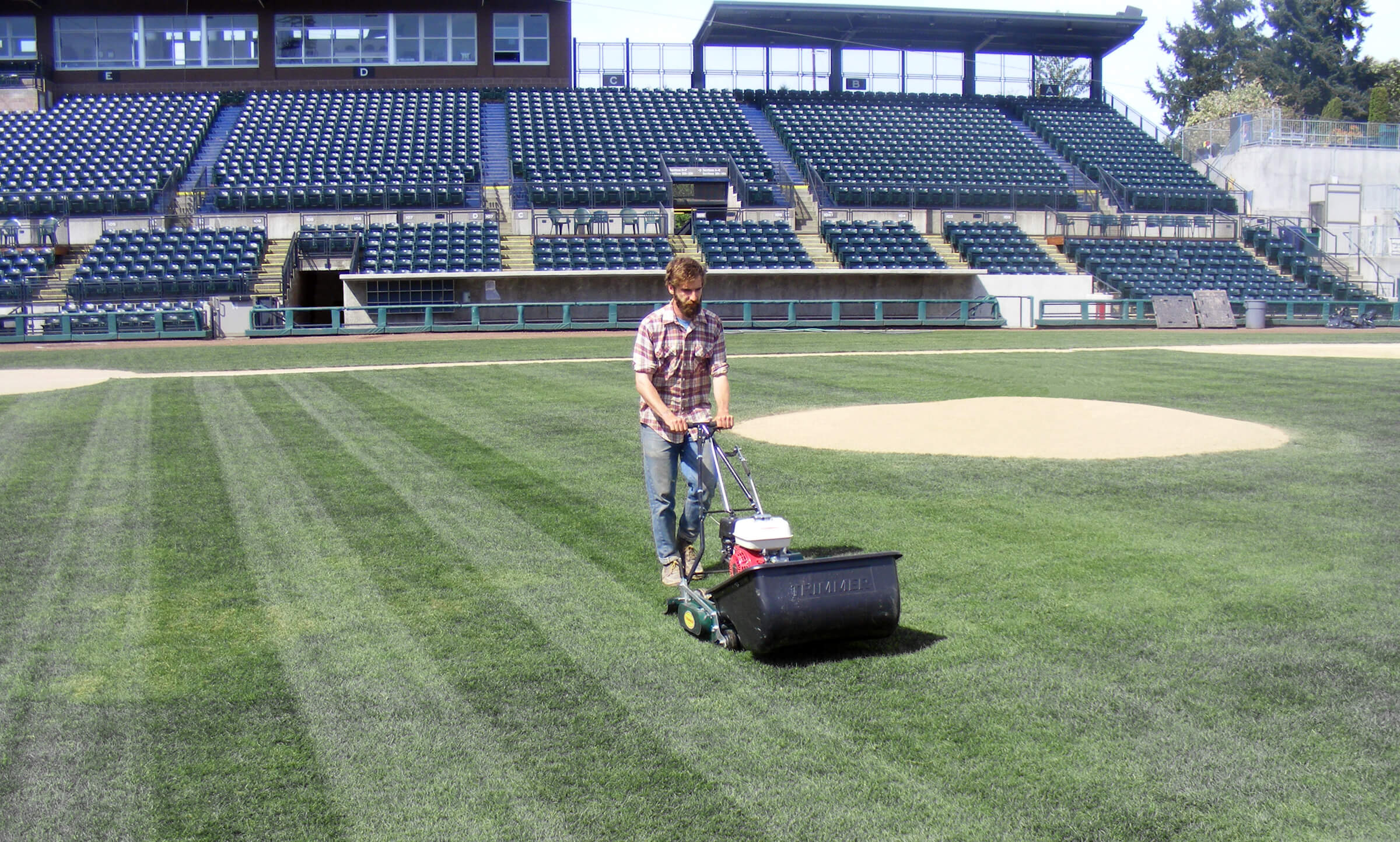 man mowing straight lines on a baseball field